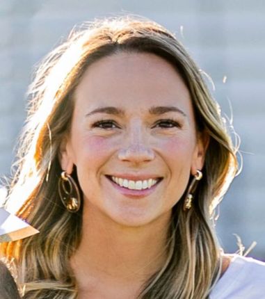 A woman wearing hoop earrings is smiling for the camera