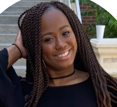 A woman with braids and a choker smiles for the camera