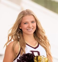 A cheerleader is holding a bunch of pom poms and smiling for the camera.