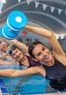 A group of people are lifting dumbbells in a swimming pool.