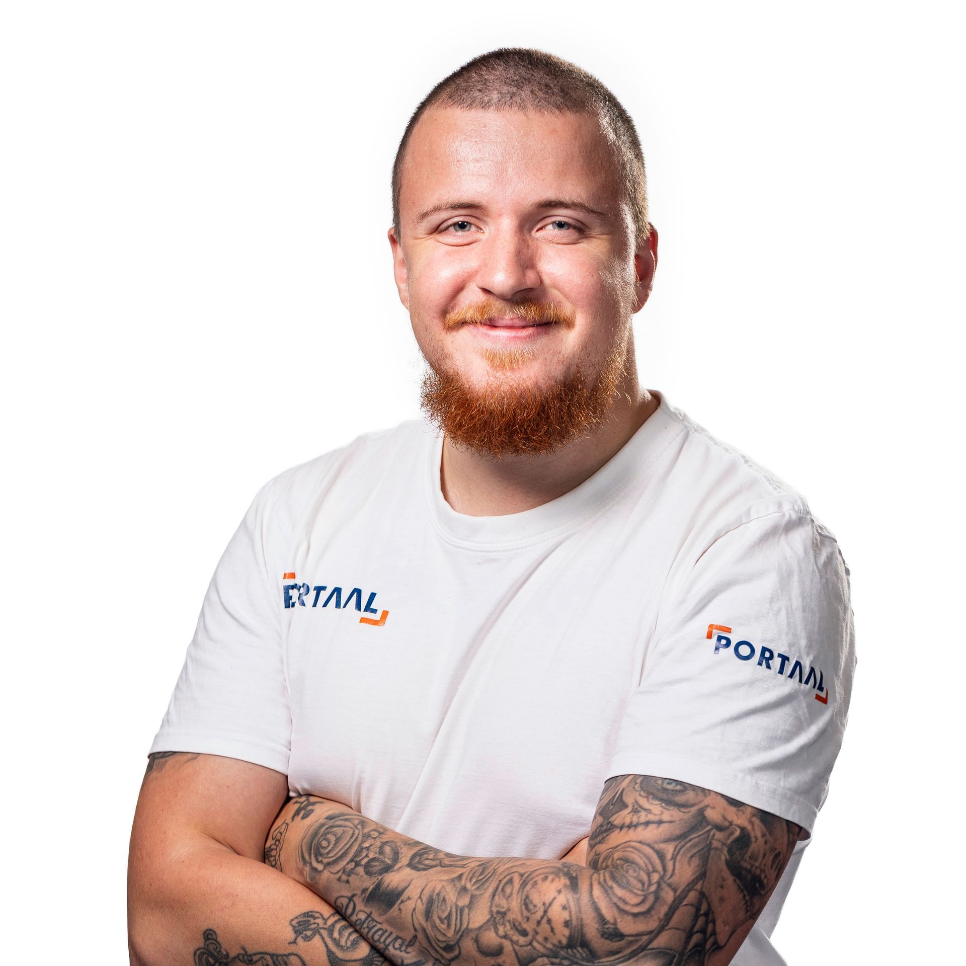 Een man met kort haar en een rode baard, lachend, met de armen over elkaar, draagt ​​een wit