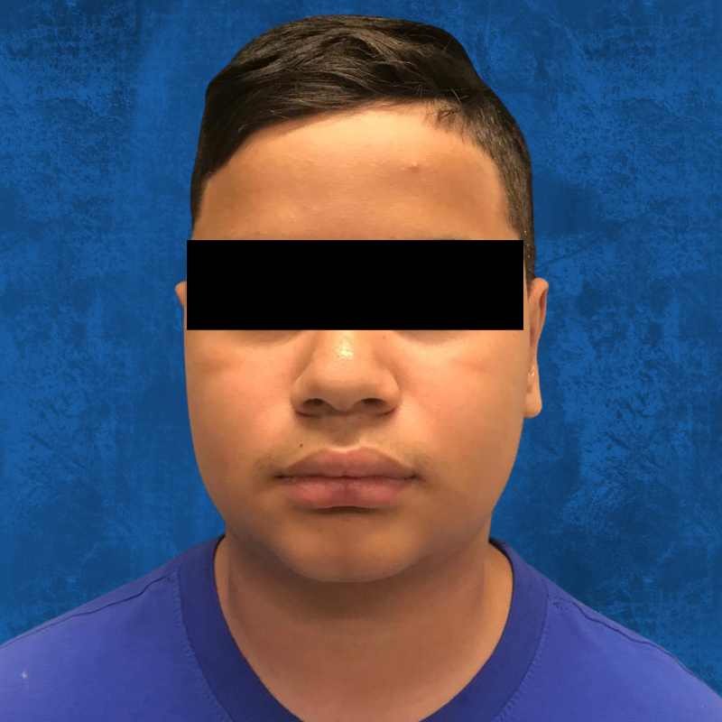 A person wearing a blue shirt against a blue background, with their eyes obscured by a black bar.