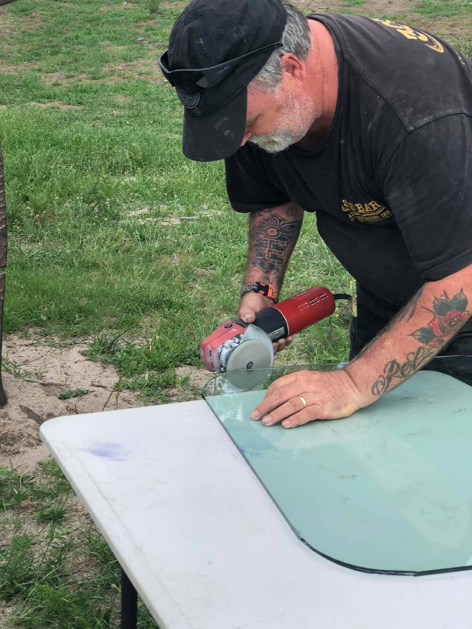 Man Carefully Cutting The Windshield For Replacement