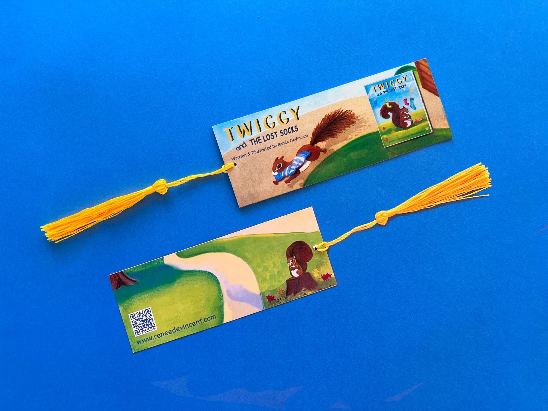 Two bookmarks with a picture of a squirrel on them are on a blue surface.