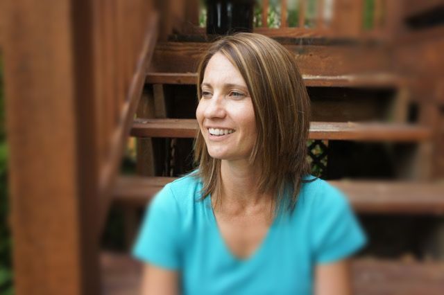 A woman in a blue shirt is sitting on a set of wooden stairs.