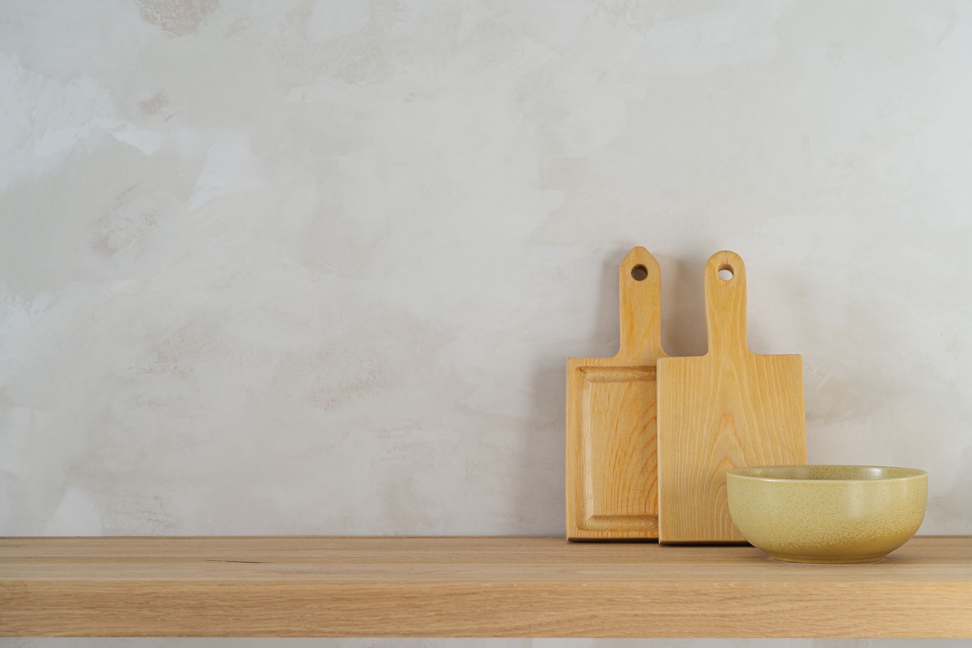 Uno scaffale di legno con sopra due taglieri di legno e una ciotola.