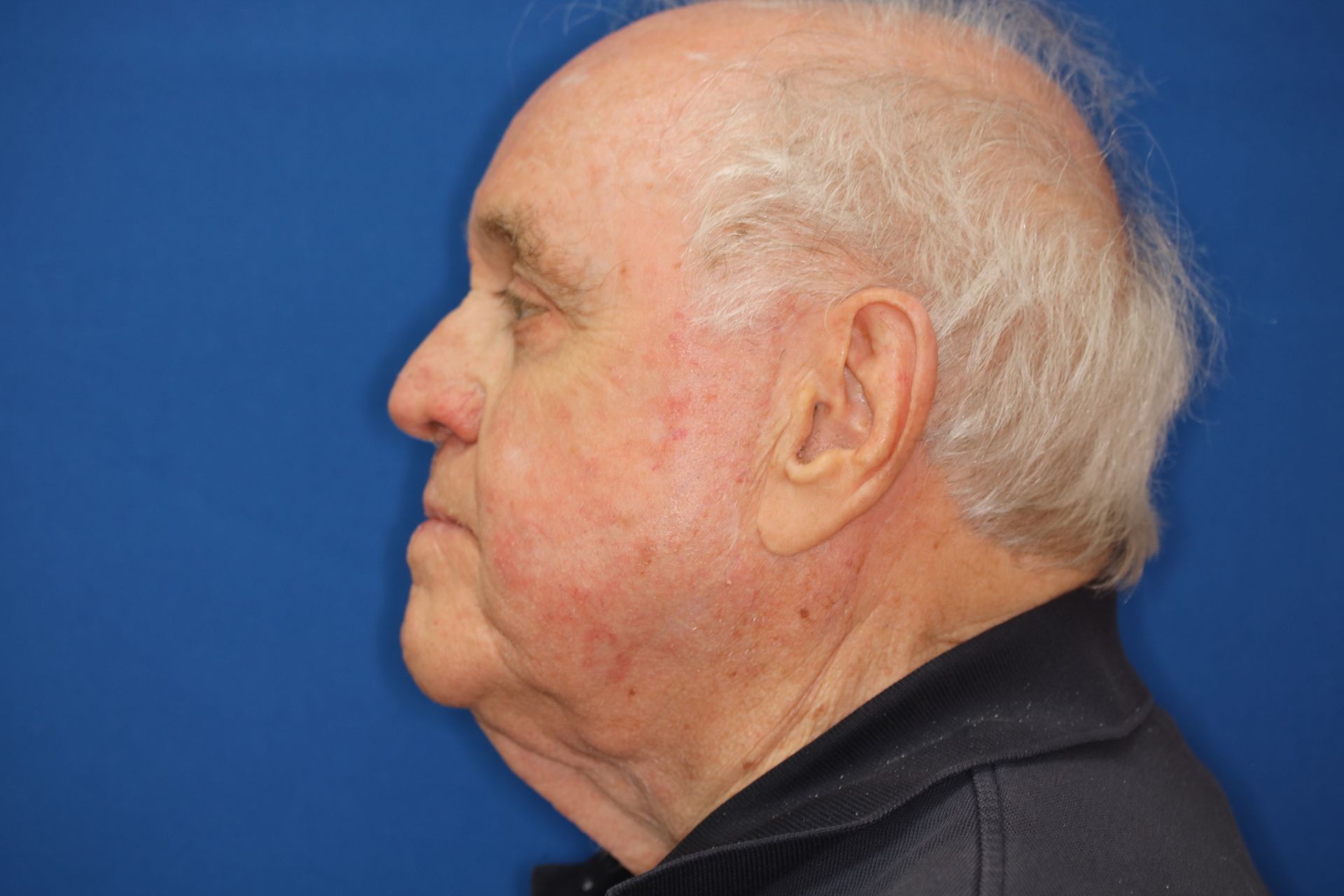 A close up of an older man 's face against a blue background.