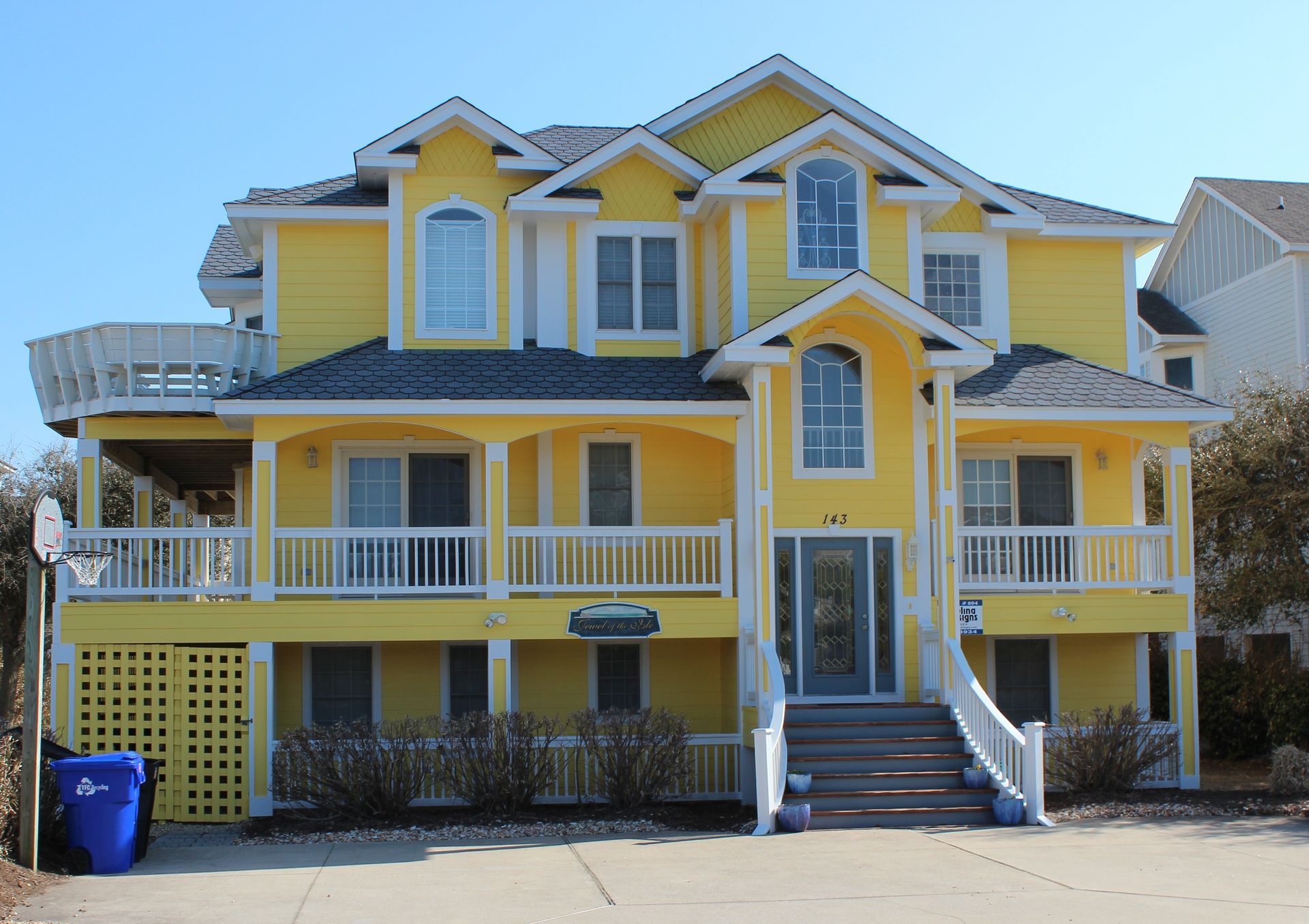 Yellow multi-story house with white trim and a blue sky.