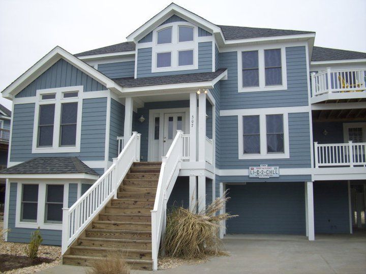 Blue two-story beach house with white trim, stairs, and windows.