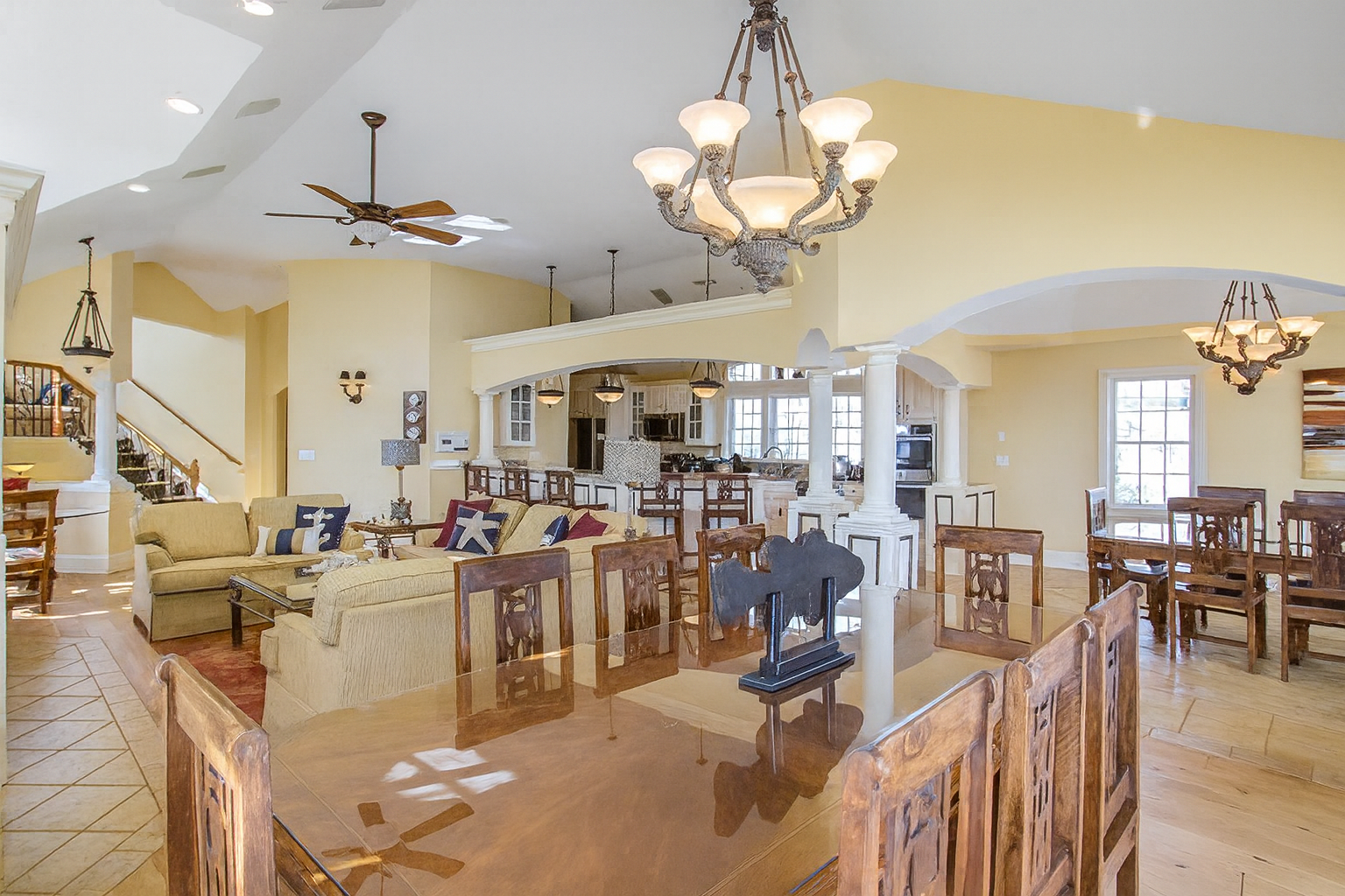 Spacious open-concept living/dining area with light yellow walls, wood dining set, and chandeliers.