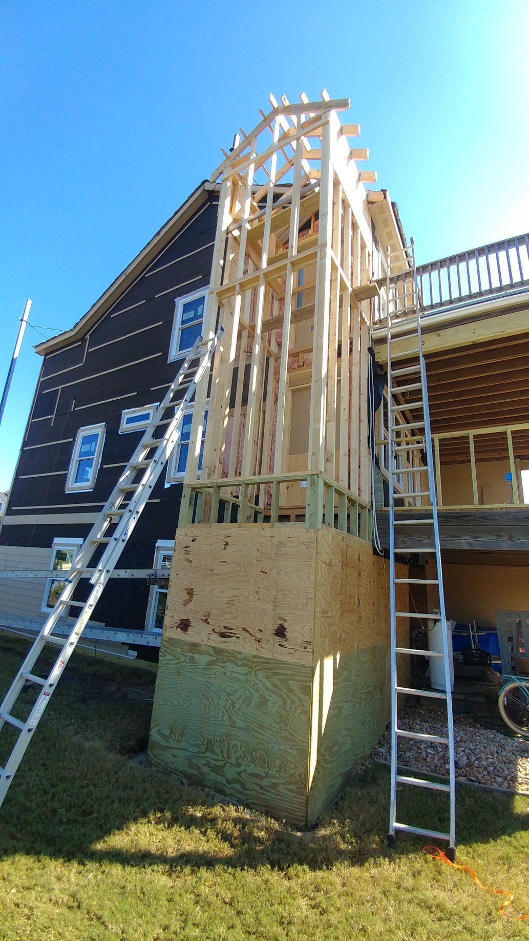 Construction site: Wooden frame of a building addition on a house with ladders and insulation.