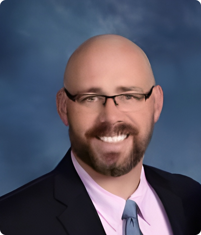 Bald man with glasses, a beard, and a suit jacket smiling at the camera.