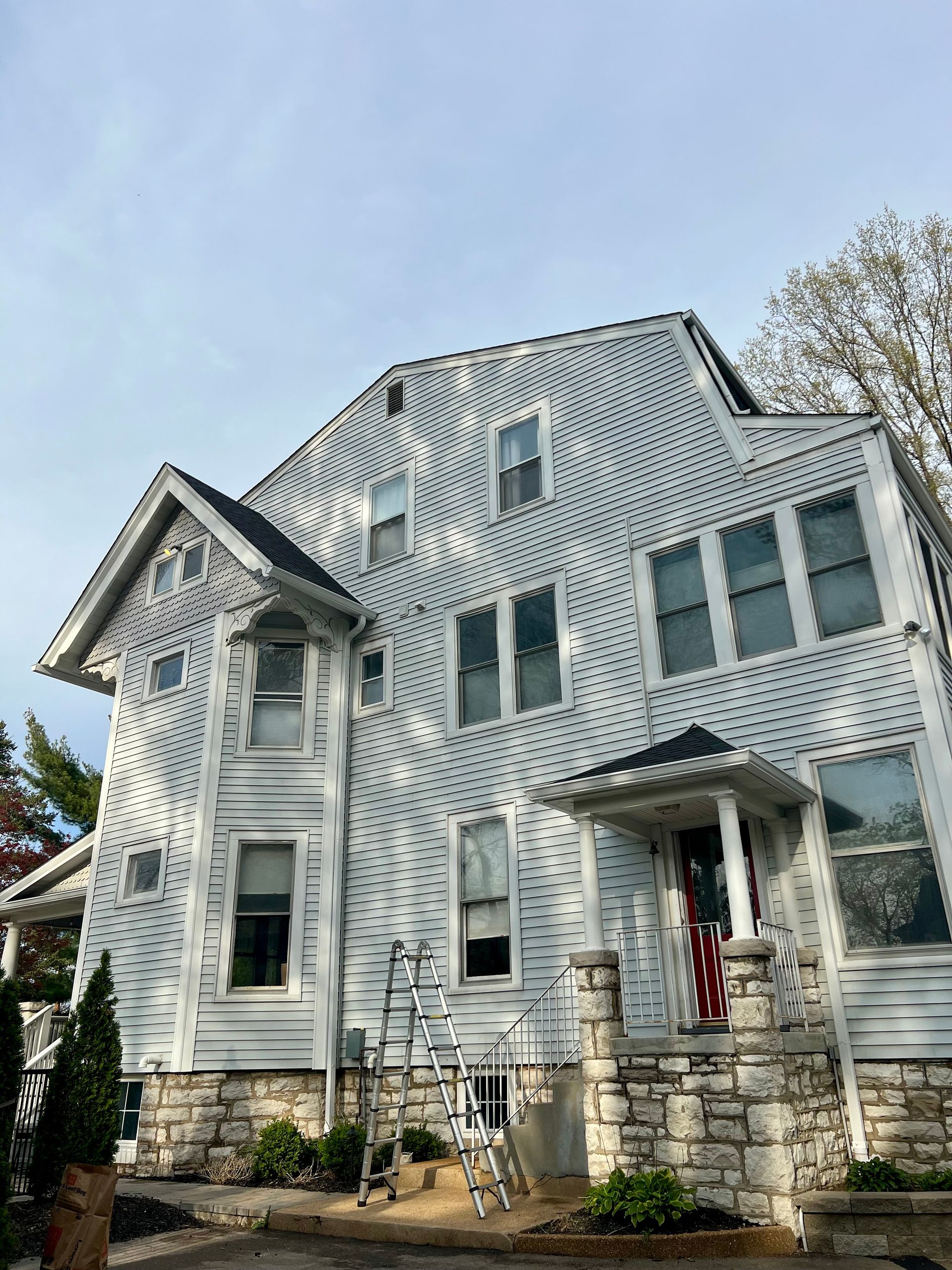A large, multi-story house covered in a distinctive, repeating pattern of small black circular dots on white siding.