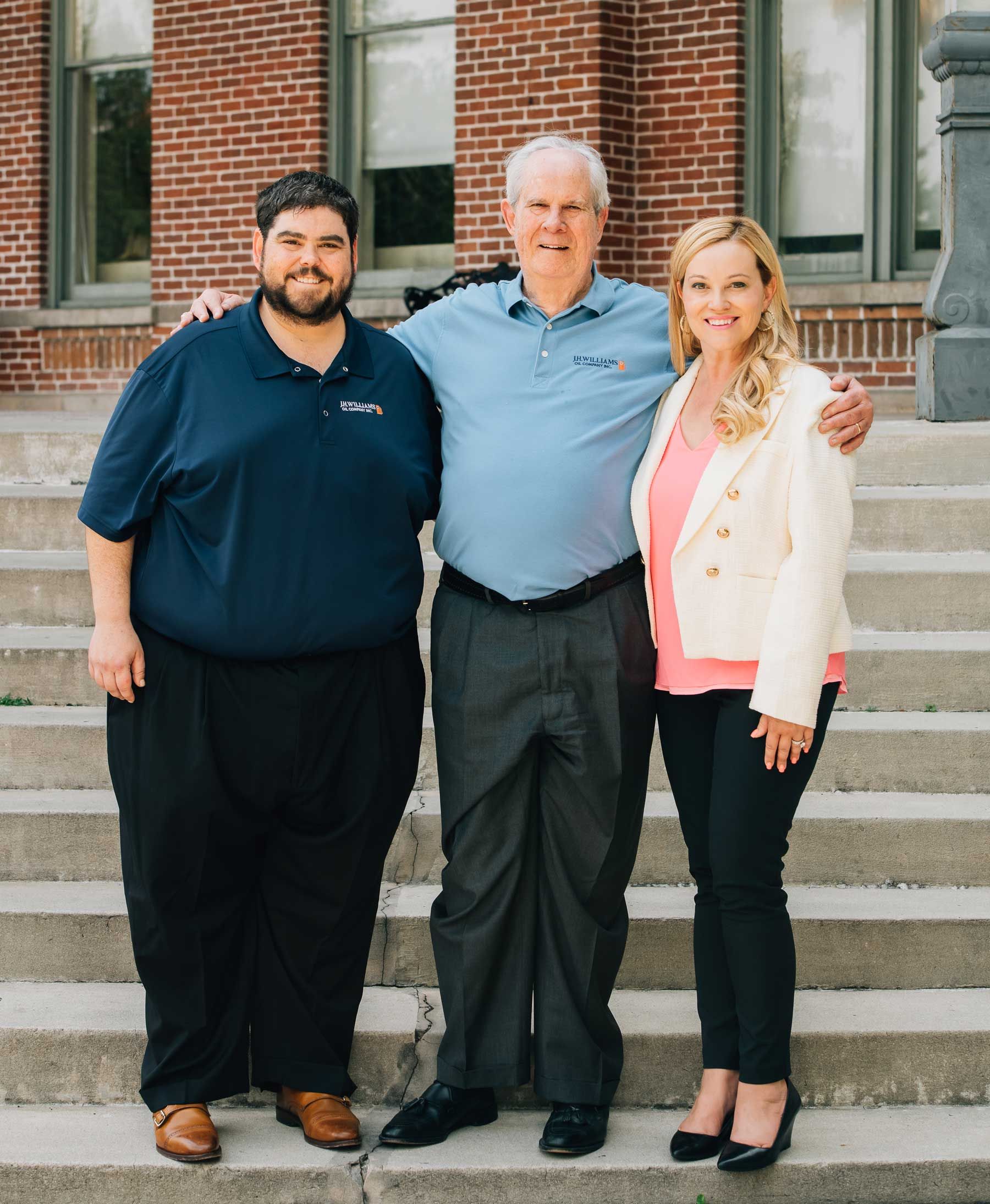 Three people are posing for a picture on the steps of a building