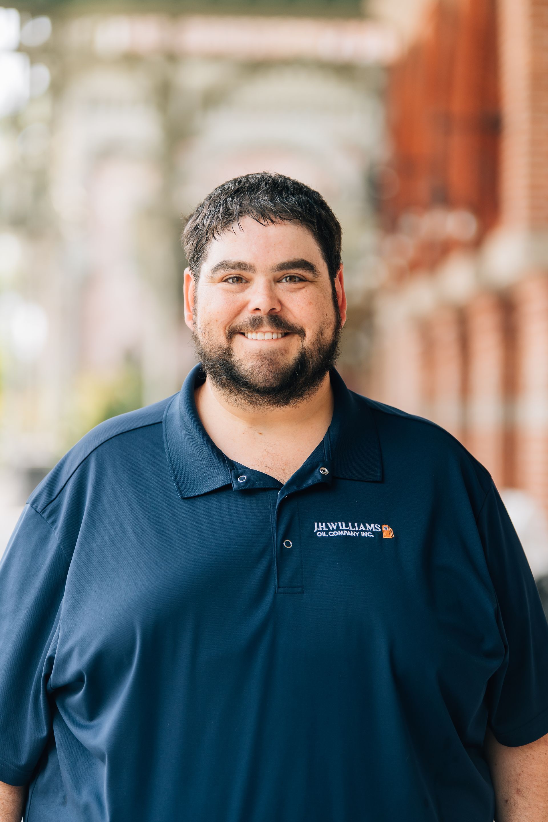 A man with a beard is wearing a blue polo shirt and smiling. A man with a beard is wearing a blue polo shirt and smiling.