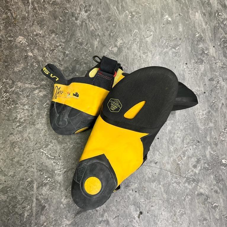 Yellow and black climbing shoes on a gray surface.