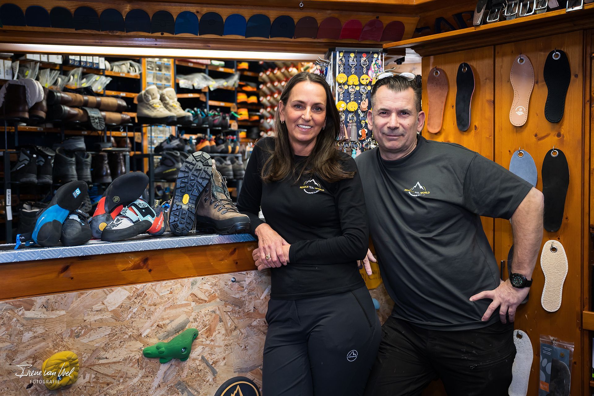Two people, a woman and a man, standing in a shop, both wearing branded shirts, smiling.