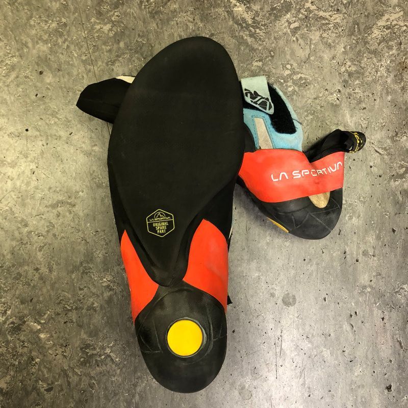 Climbing shoe, black rubber sole with red and black upper, yellow heel. LA SPORTIVA logo visible.