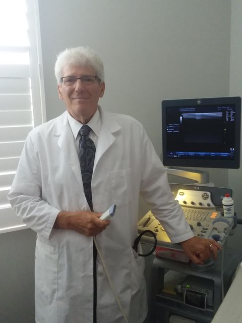A man in a lab coat stands in front of an ultrasound machine