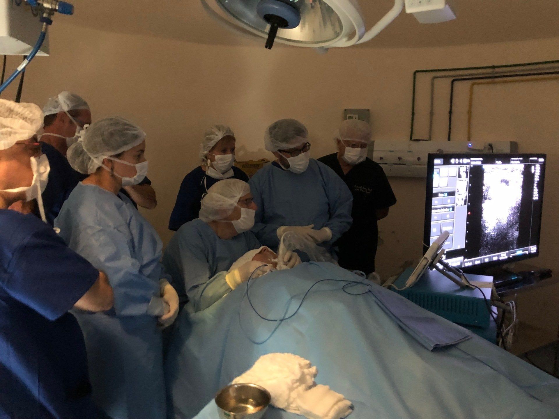 A group of surgeons are operating on a patient in an operating room.