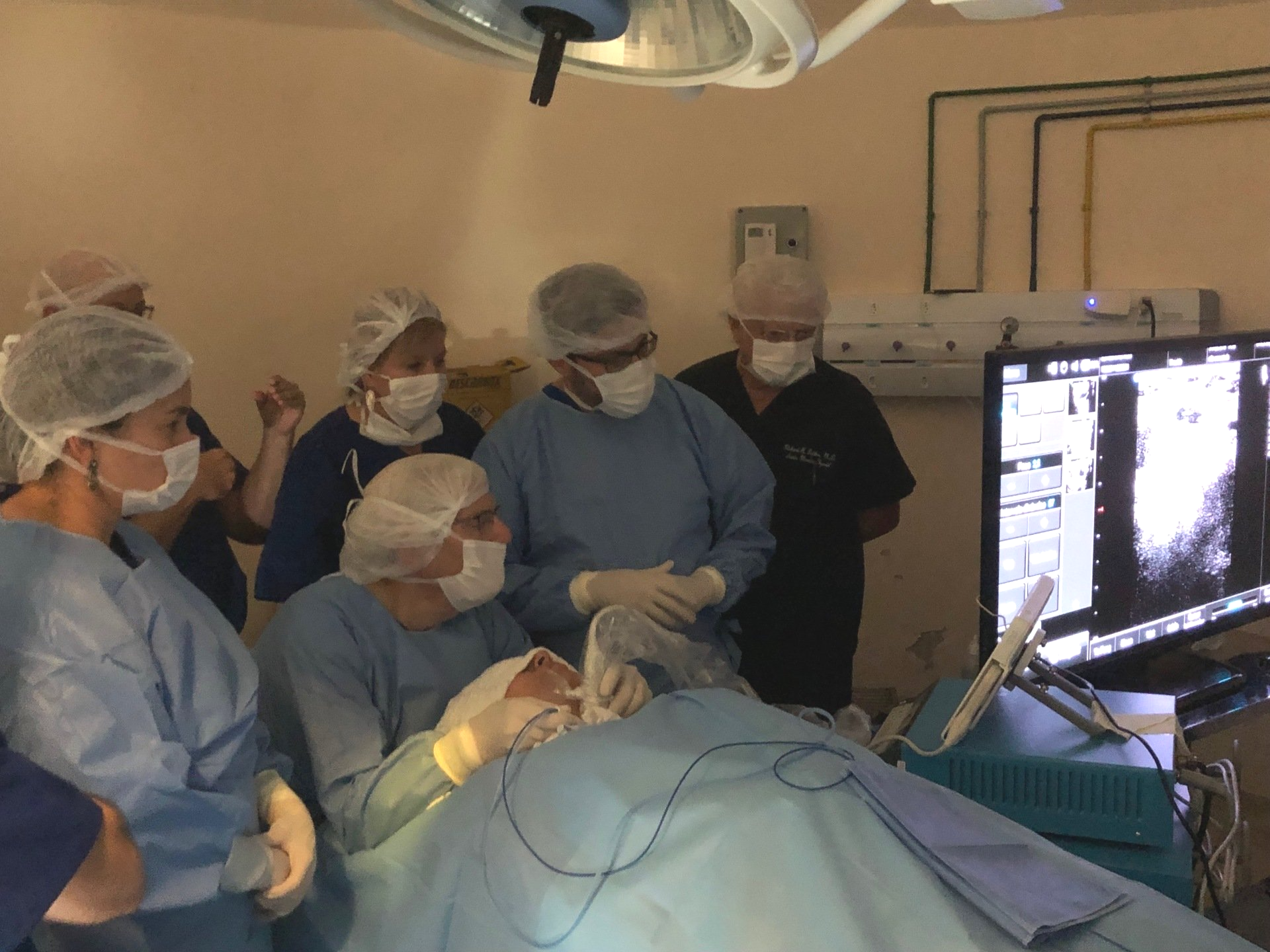 A group of surgeons are working on a patient in an operating room