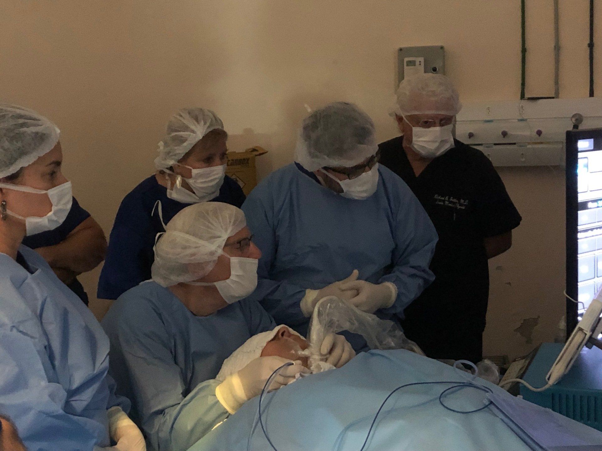 A group of surgeons are working on a patient in an operating room