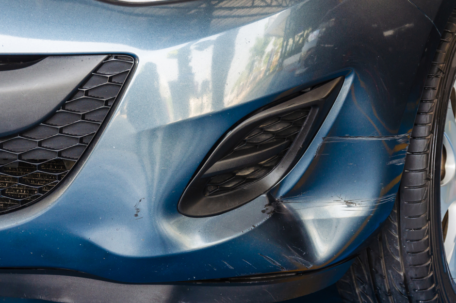 a close up of a blue car with a damaged bumper .