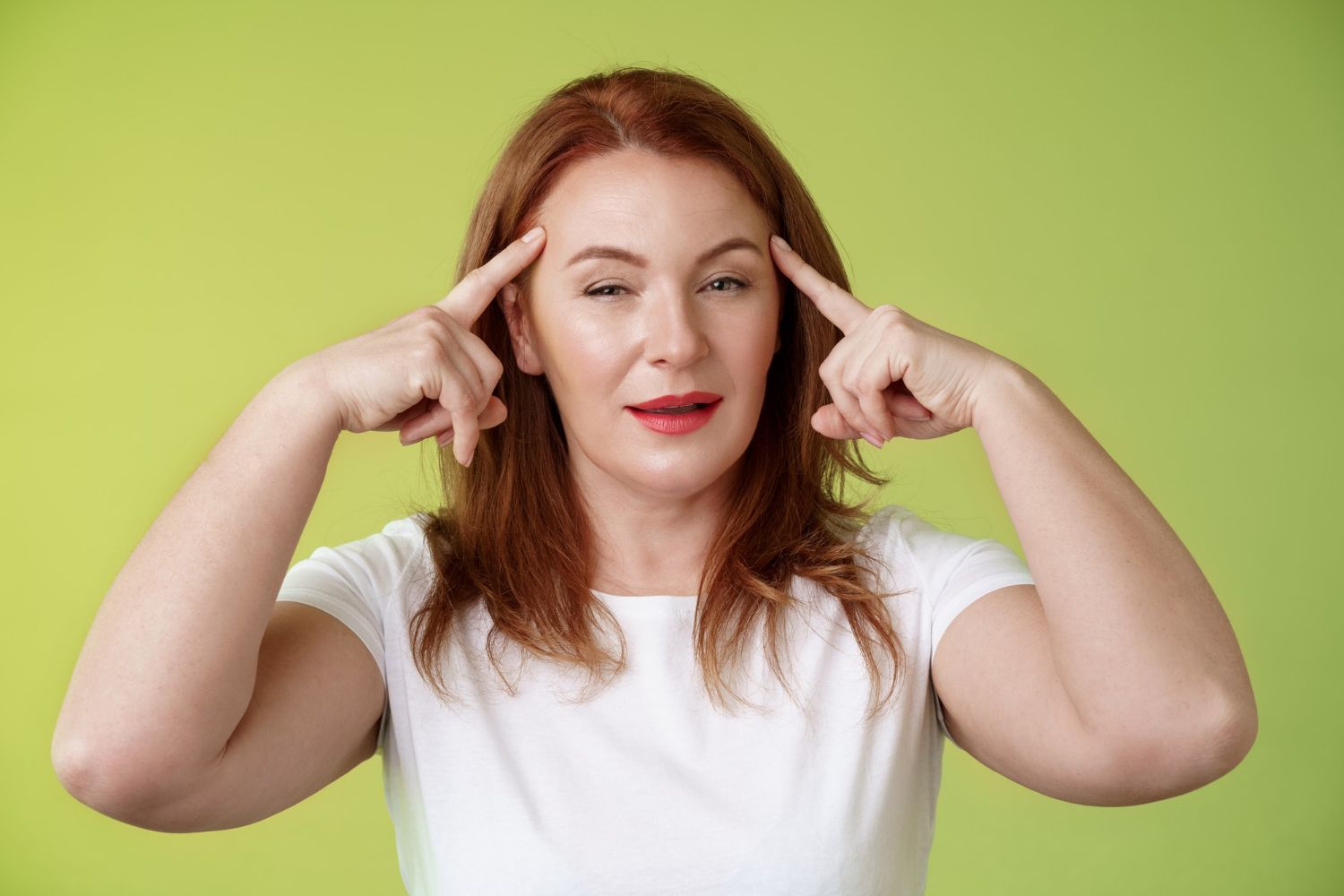 A woman is making a funny face with her hands on her head.