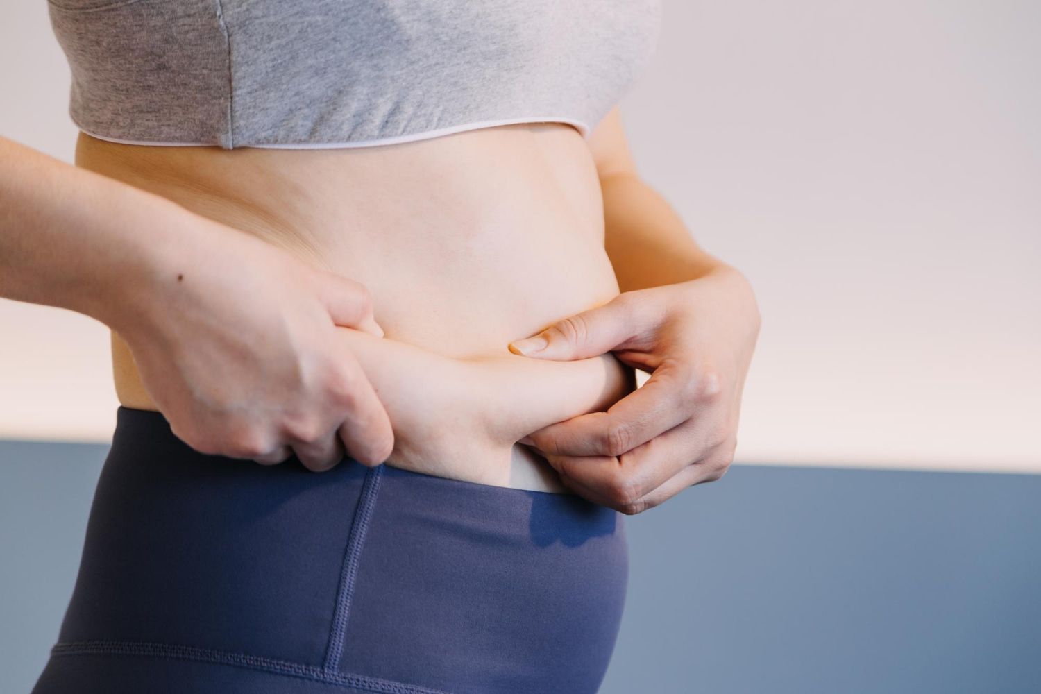 A woman is holding her stomach with her hands.
