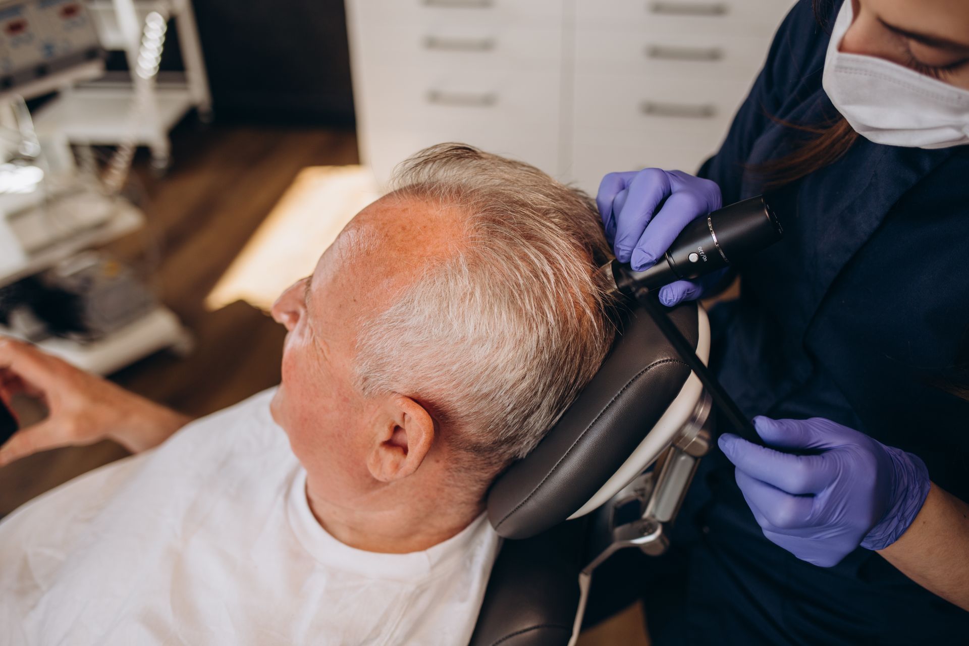 Dentist wearing purple gloves and mask treating a seated patient in a dental chair