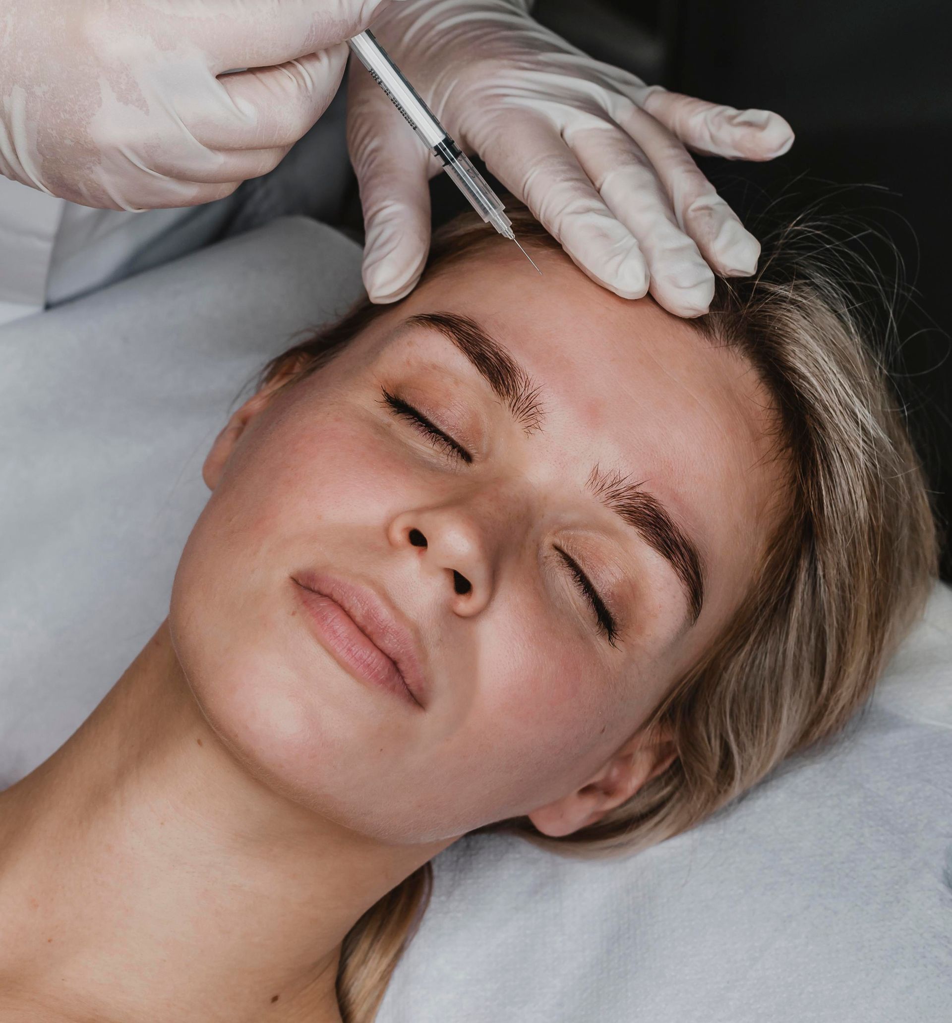 A man is getting an injection in his forehead by a doctor.