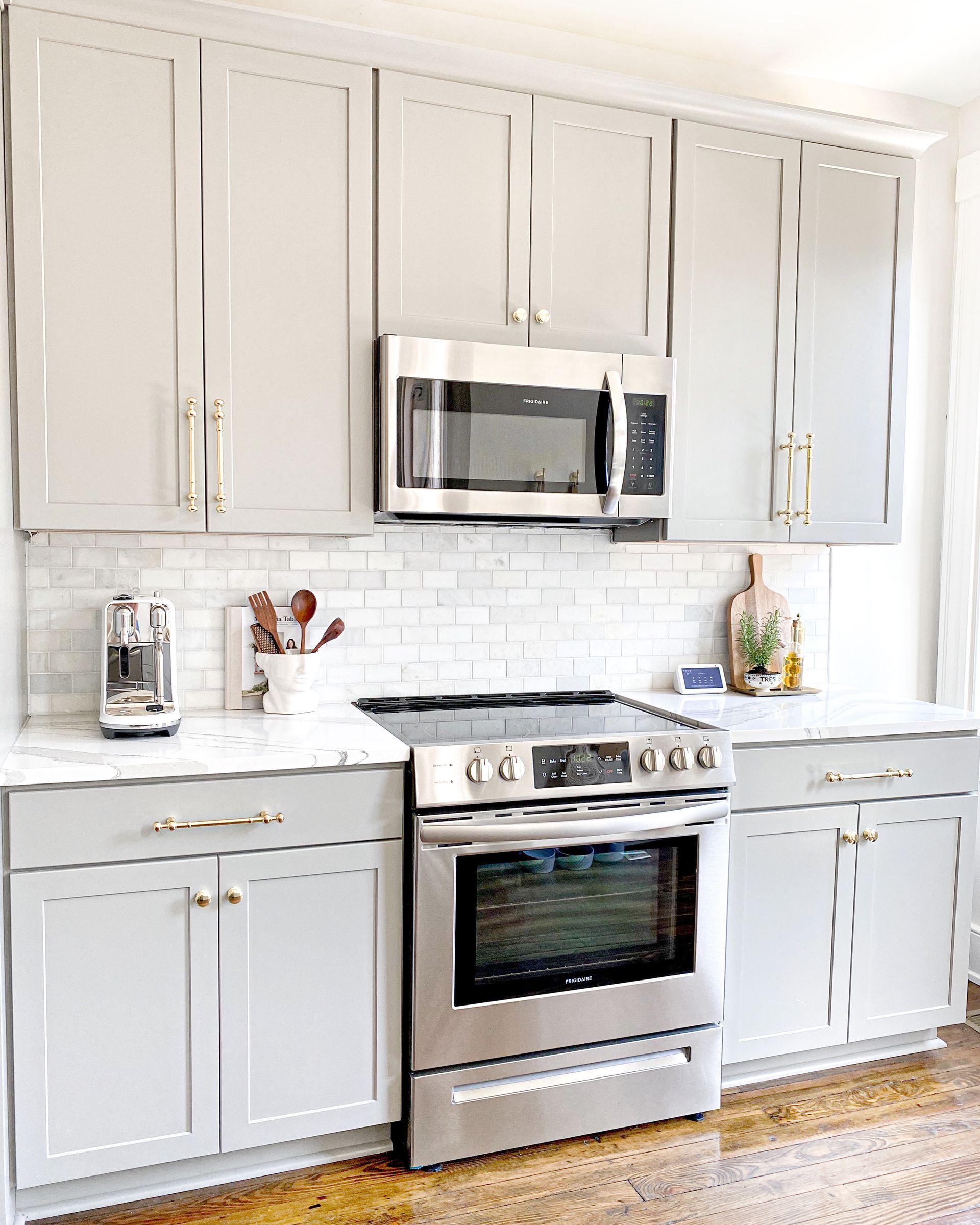 An elegant white kitchen cabinet with a built-in microwave oven on top of a kitchen stove.