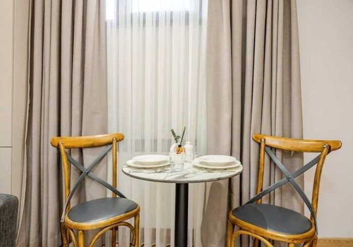 A small table with two chairs in front of a window.