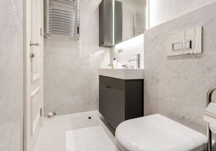 A bathroom with a toilet , sink and mirror.