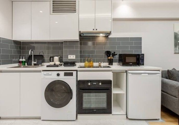 A kitchen with a washing machine , oven , dishwasher and microwave.