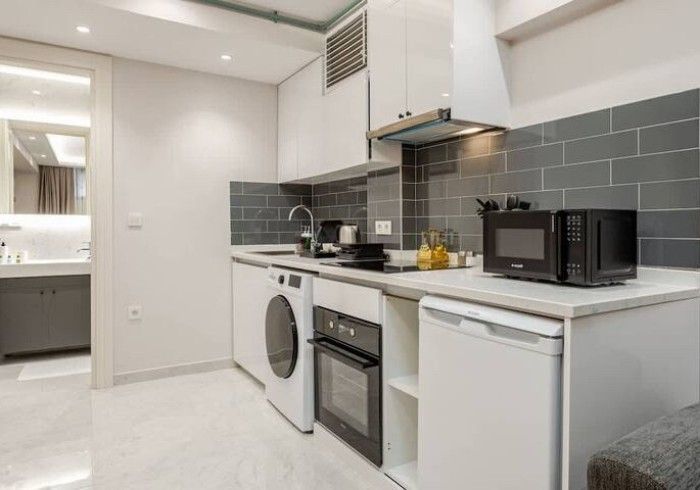 A kitchen with a washing machine , oven , microwave and refrigerator.