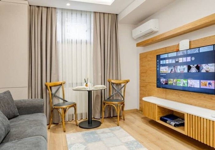 A living room with a couch , chairs , table and television.