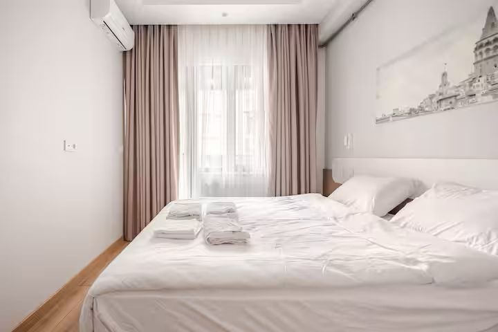 A bedroom with a bed , curtains and a window.