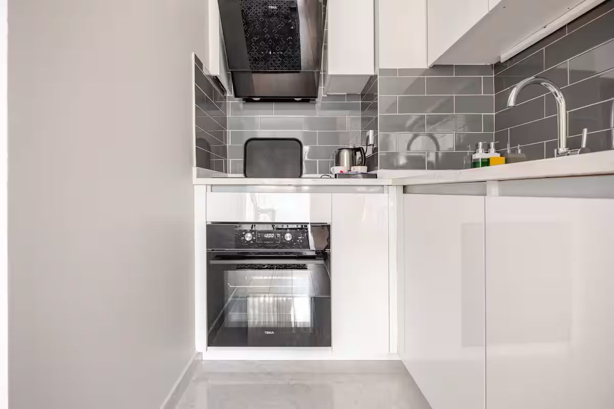 A kitchen with white cabinets , stainless steel appliances , a sink , and a stove.