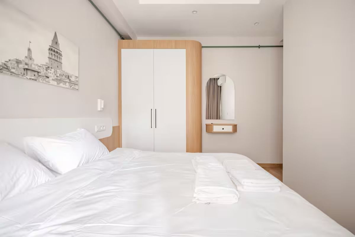 A bedroom with a bed , a wardrobe and a picture on the wall.