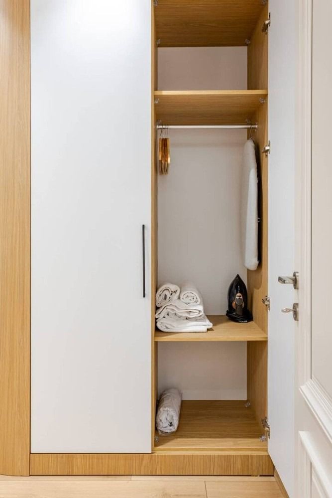 A wardrobe with a door open and clothes in it.