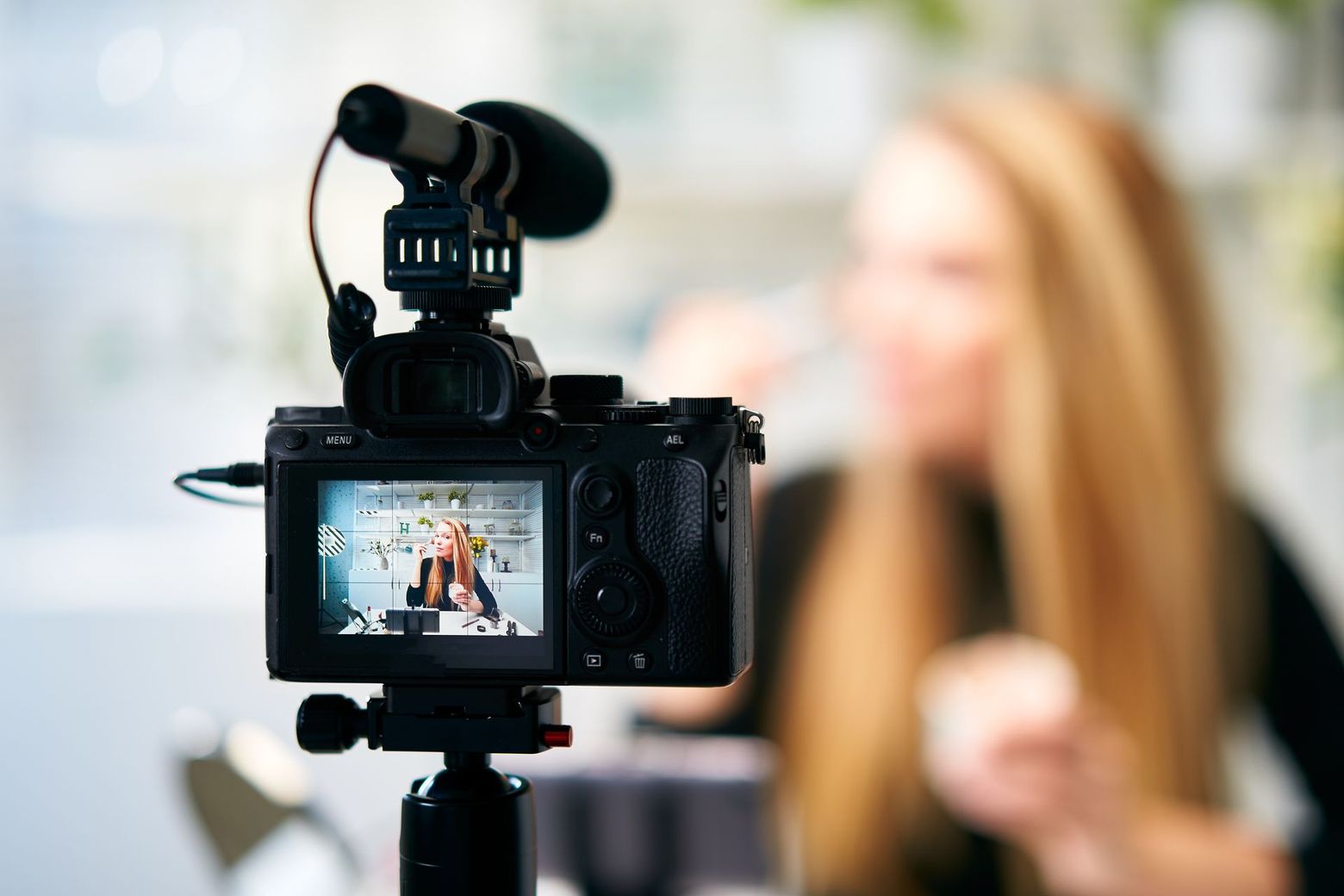 A woman is being filmed on a camera with a microphone.