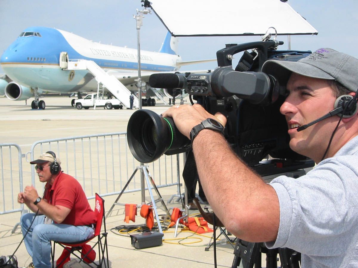 A man is holding a camera in front of an airplane