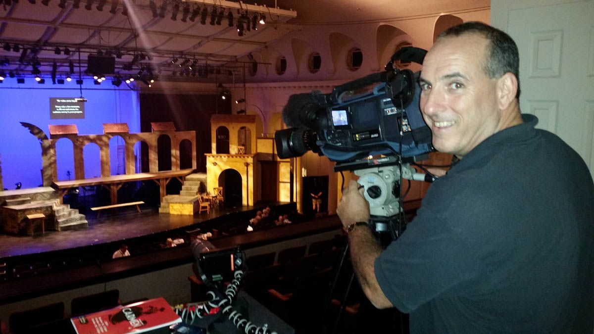 A man is holding a camera in front of a stage