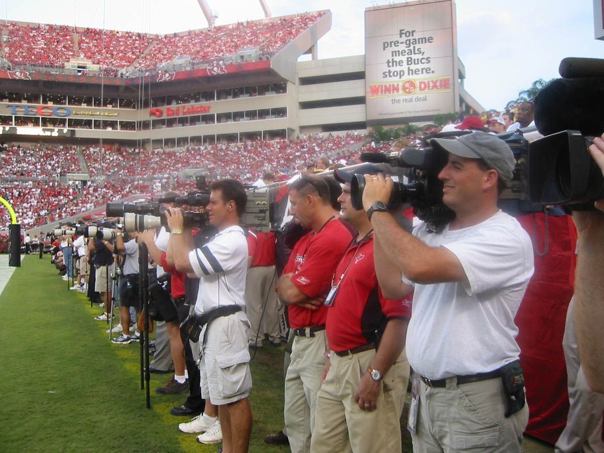 A group of men are taking pictures at a football game