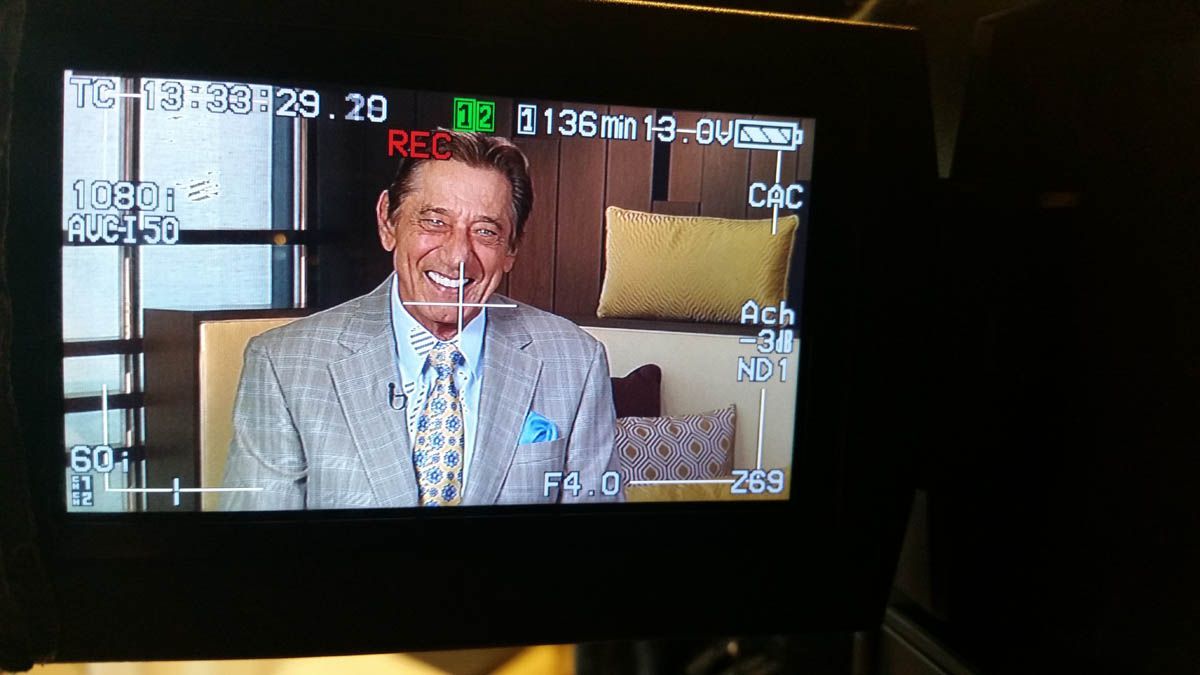 A man in a suit and tie is smiling on a tv screen