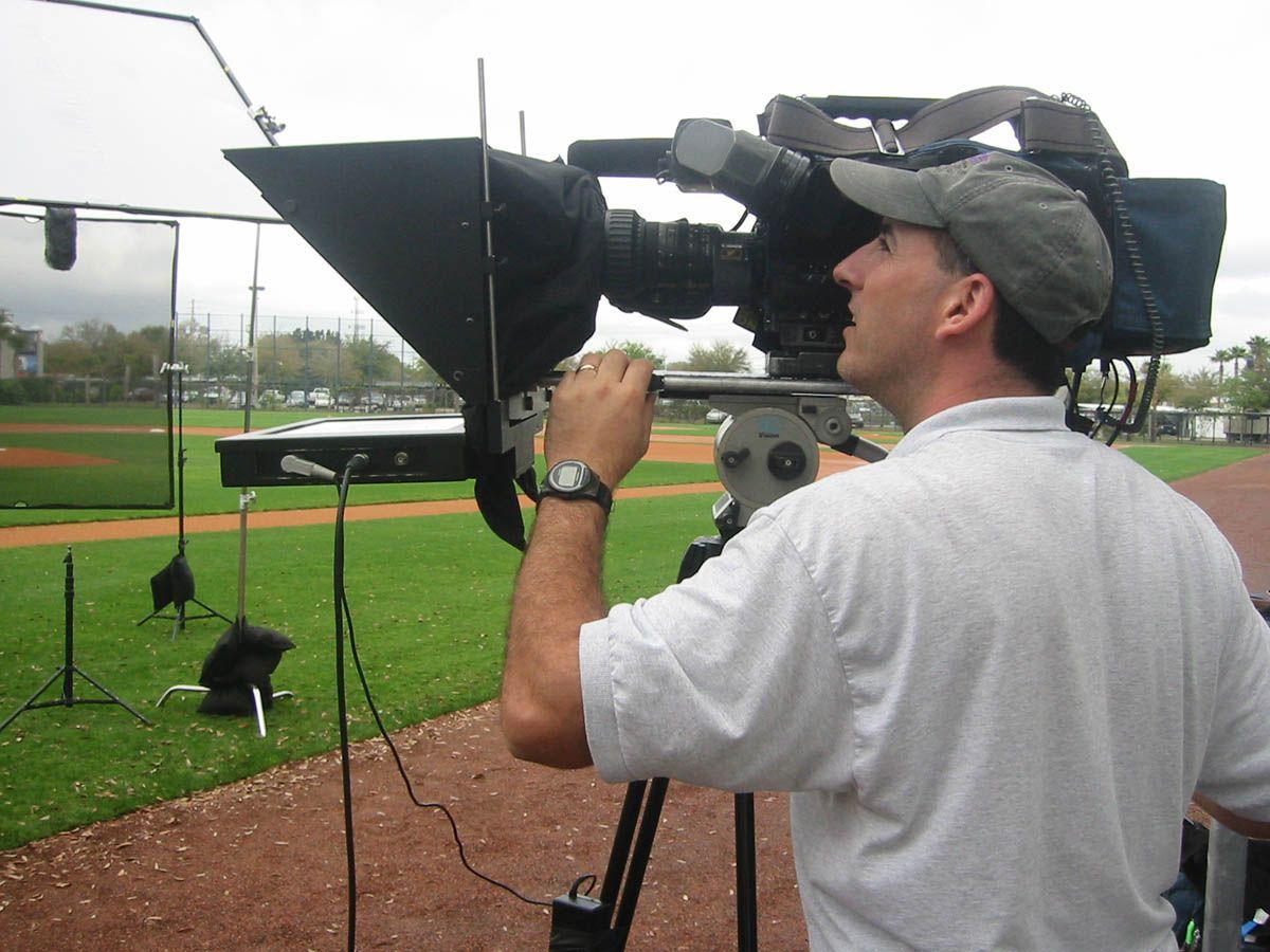A man is using a camera on a baseball field
