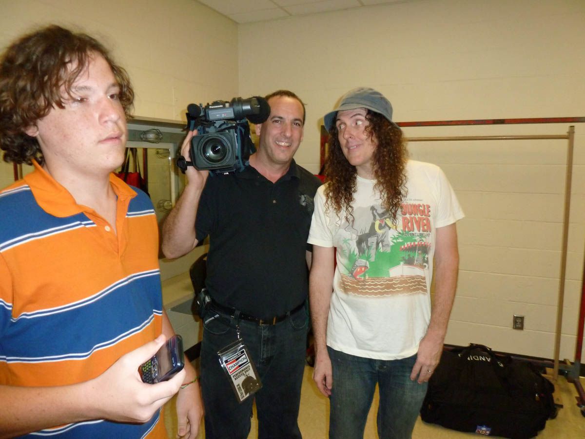 A man is holding a camera and taking a picture of two men