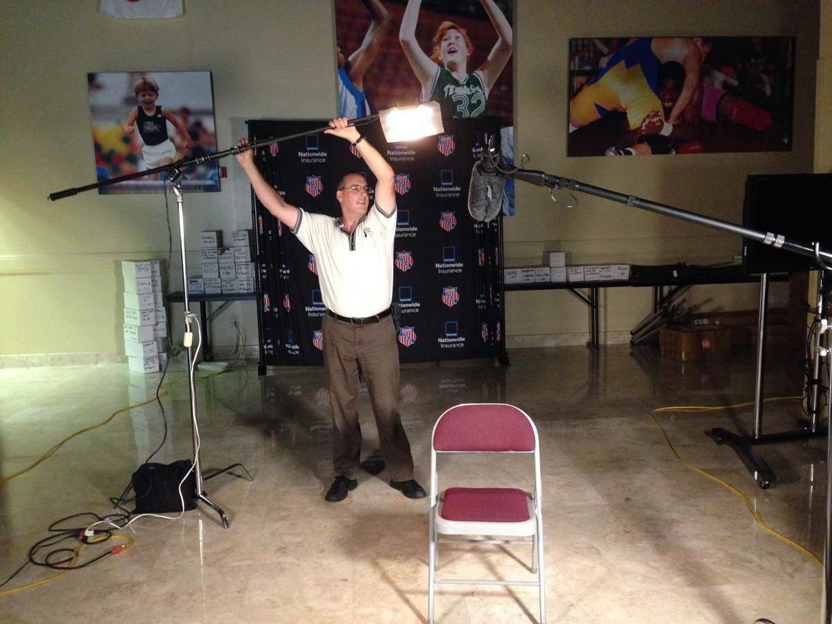 A man is standing in front of a chair with his arms in the air