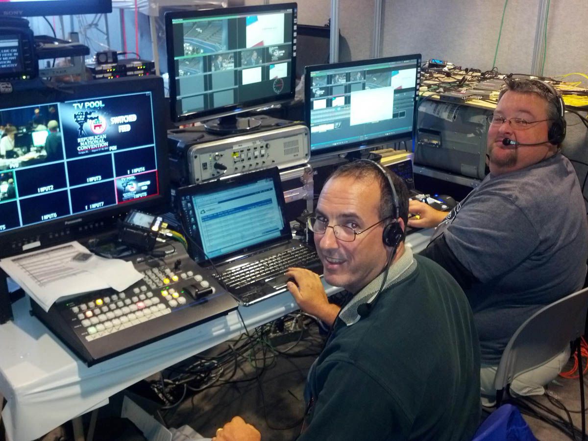 A man wearing headphones sits in front of a computer monitor